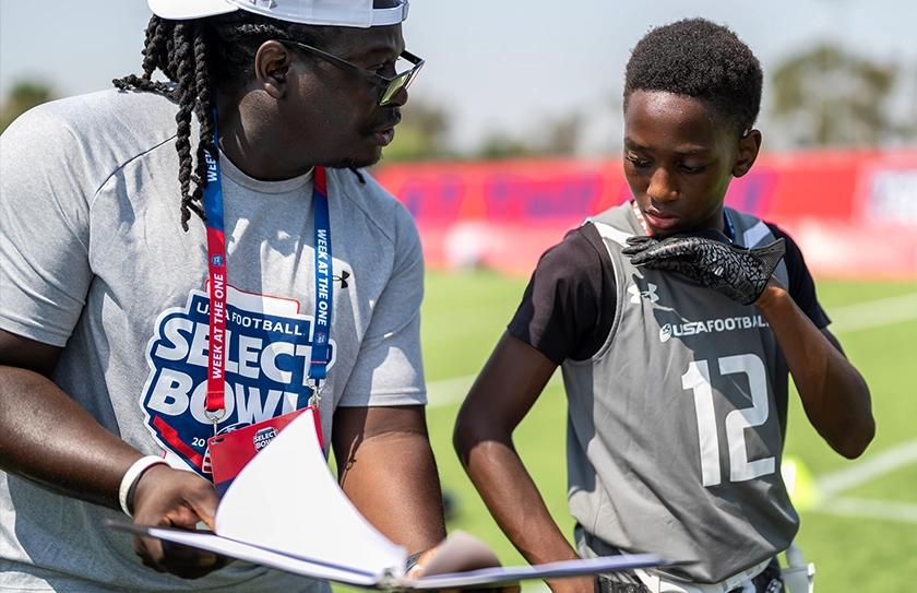 Select Bowl coach giving instruction to a boy Select Team athlete during a on the field session.